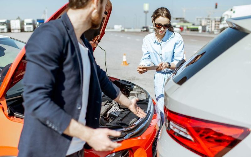 a man and a woman looking at a car engine