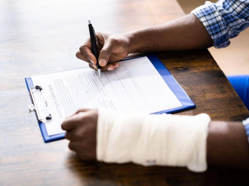 a person with a cast on their arm writing on a piece of paper