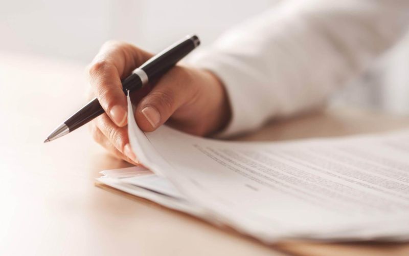 a person writing on a piece of paper with a pen