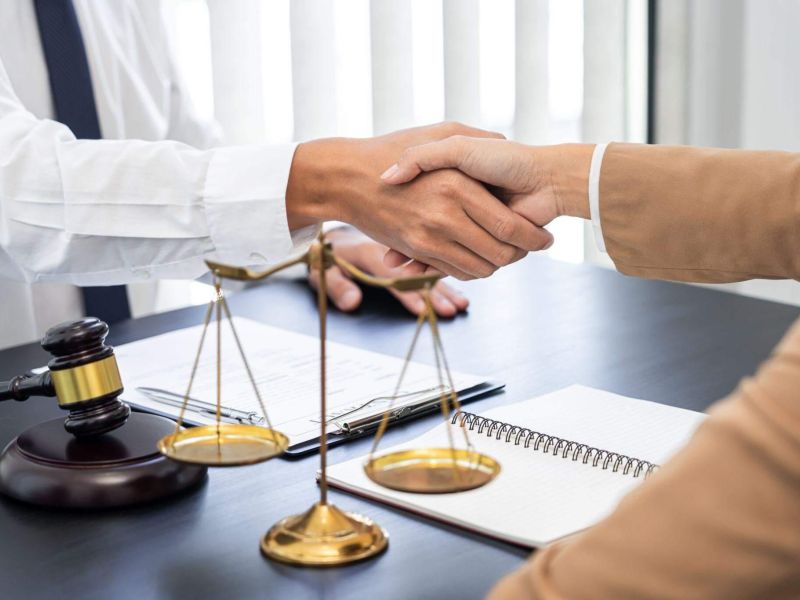two people shaking hands over a scale of justice