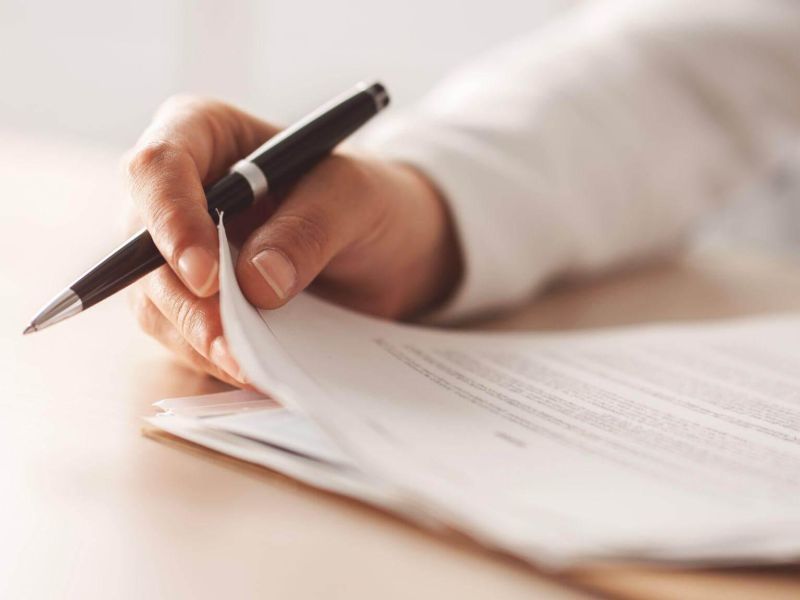 a person writing on a piece of paper with a pen