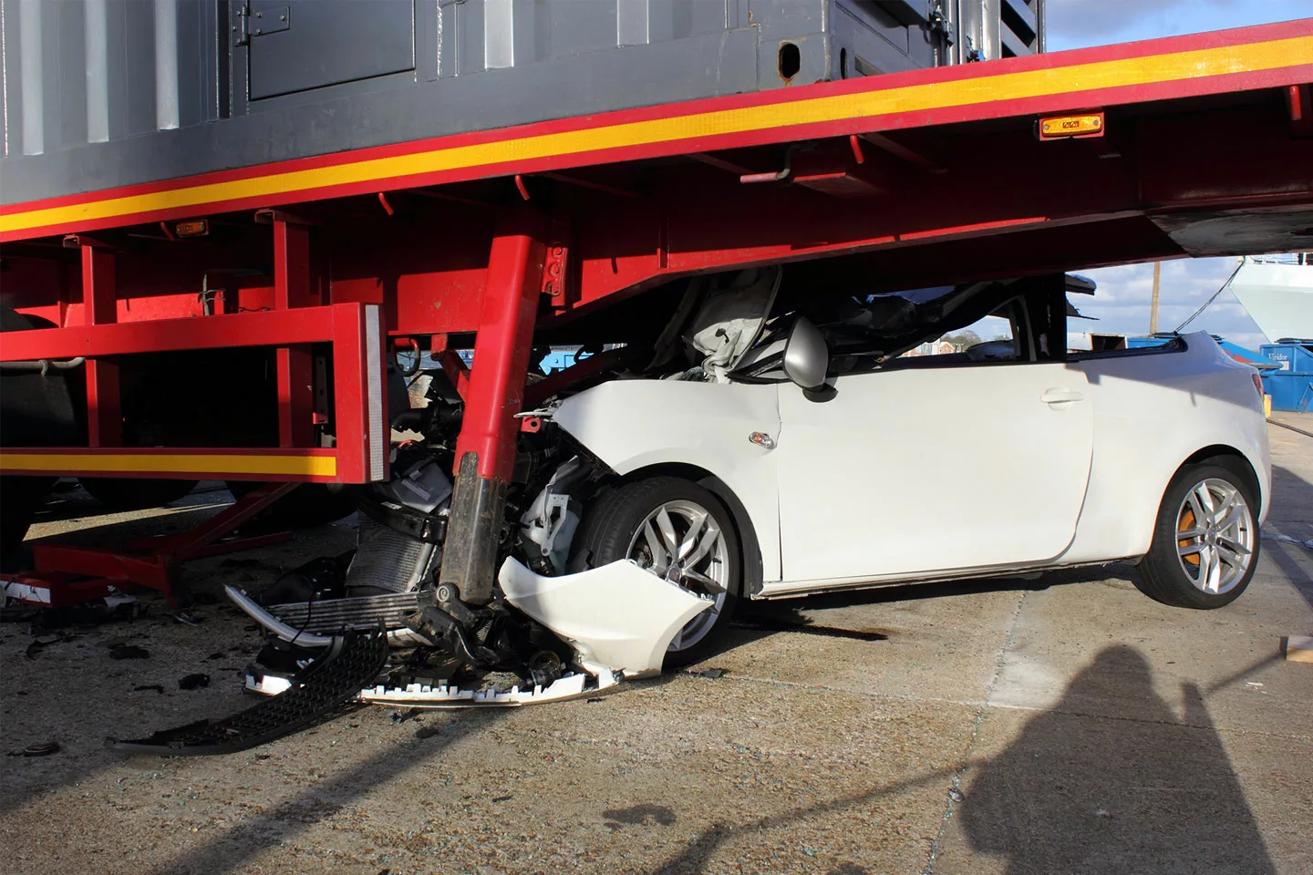 white car crashed under a semi truck