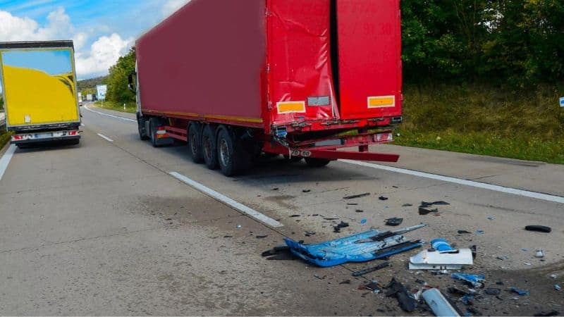 Semi truck rear ended by a blue car on the interstate
