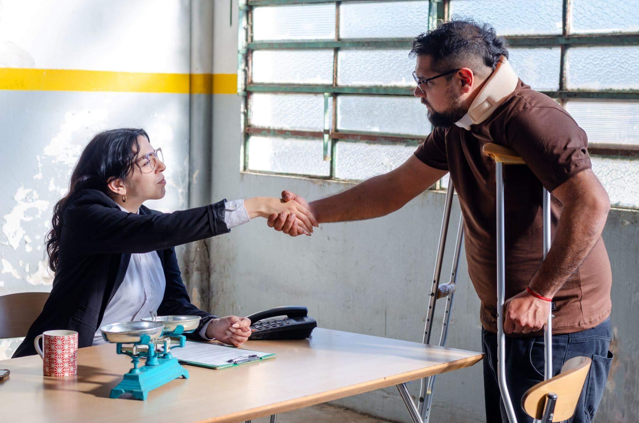 a man with walking aids shaking hands with a woman at a table