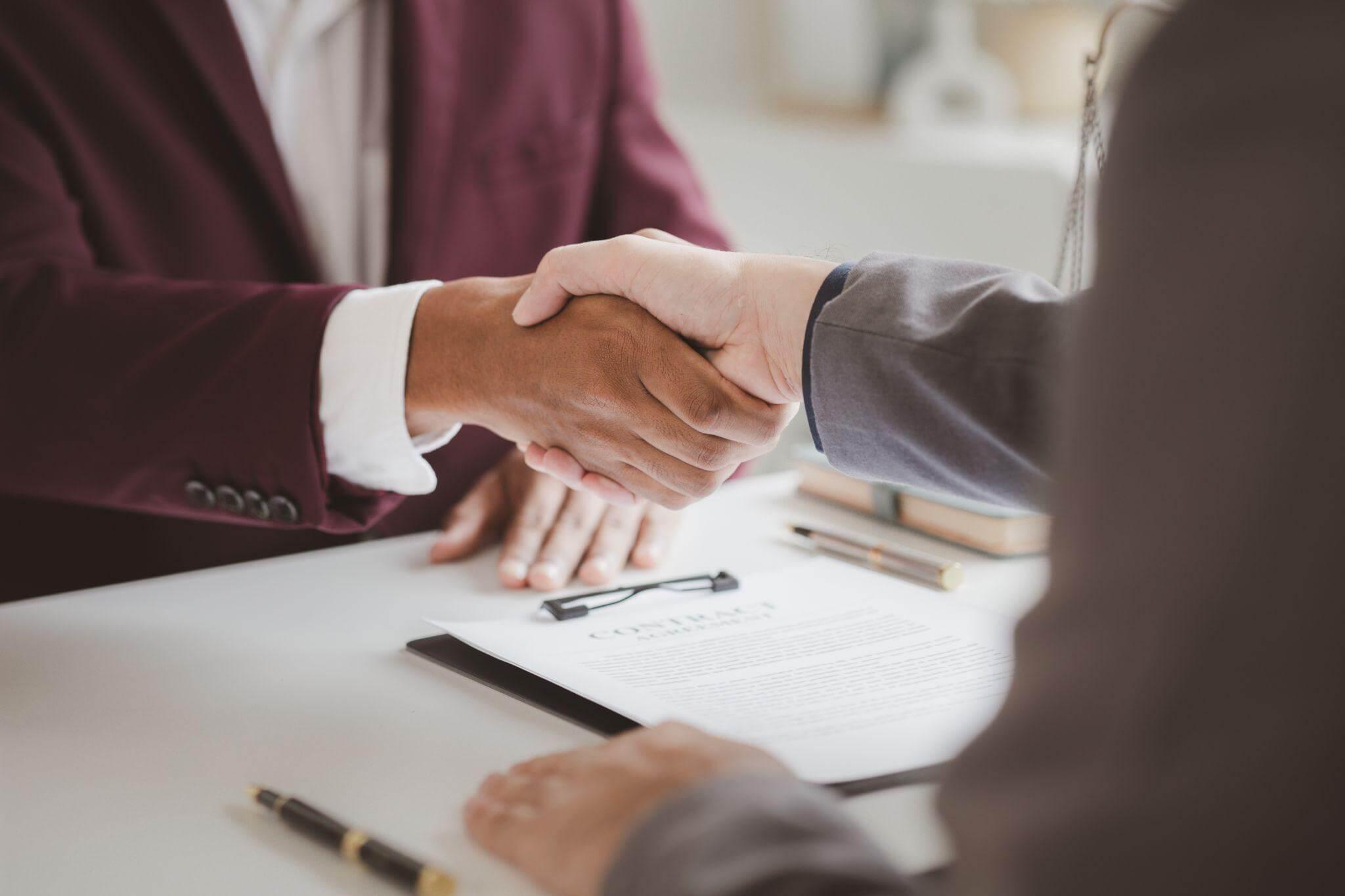 two people shaking hands over a piece of paper