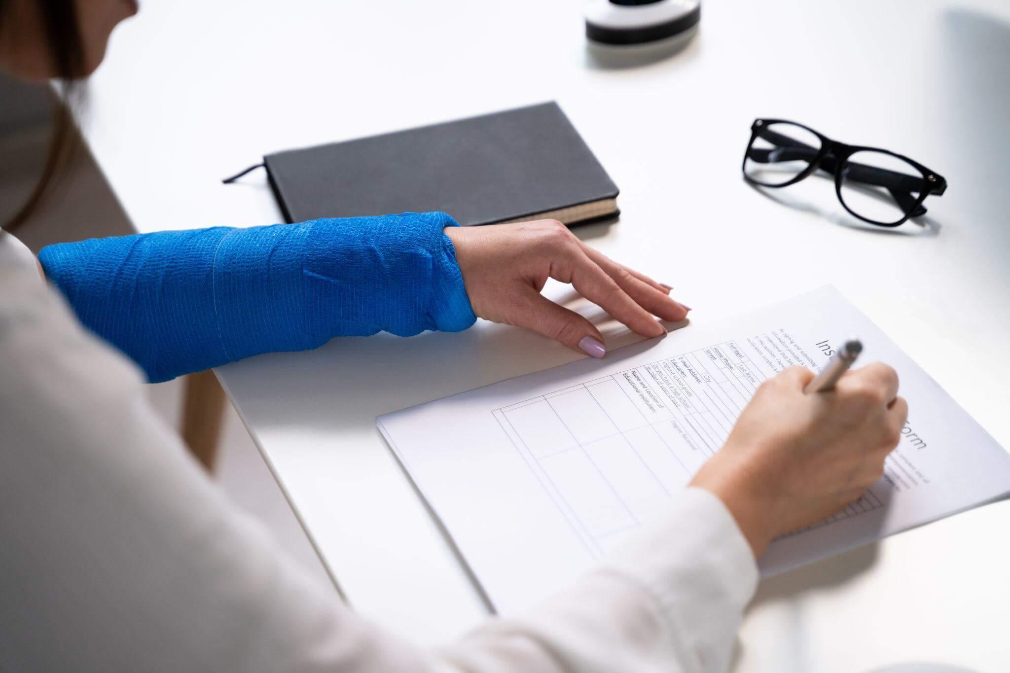 a person with a cast on their arm writing on a piece of paper