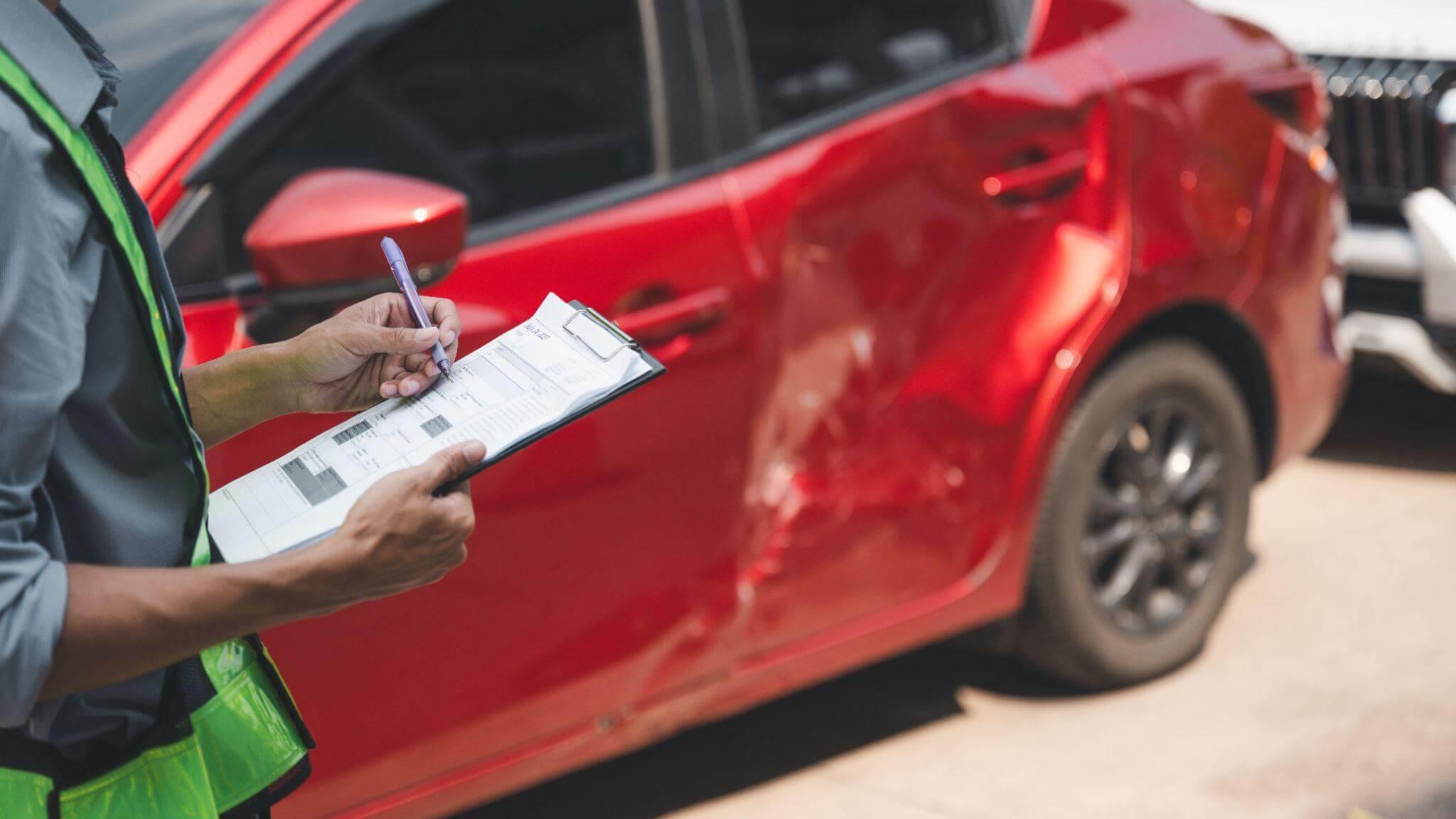 a person writing on a piece of paper next to a red car