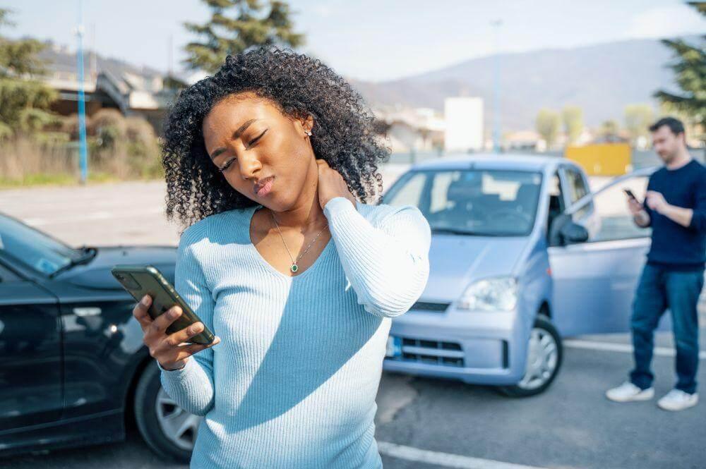 a woman standing in a parking lot looking at her cell phone